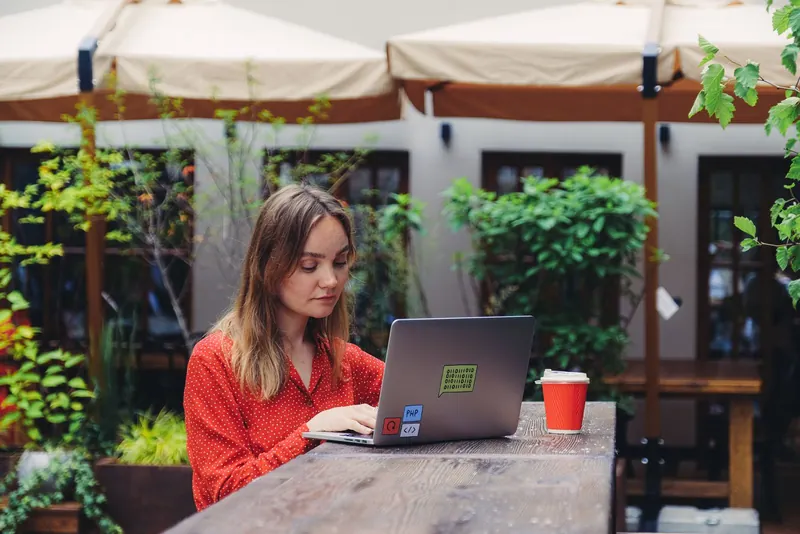 A woman working on a laptop at an outdoor café table