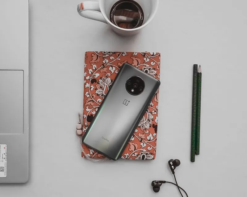 A phone and notebook beside coffee and earphones